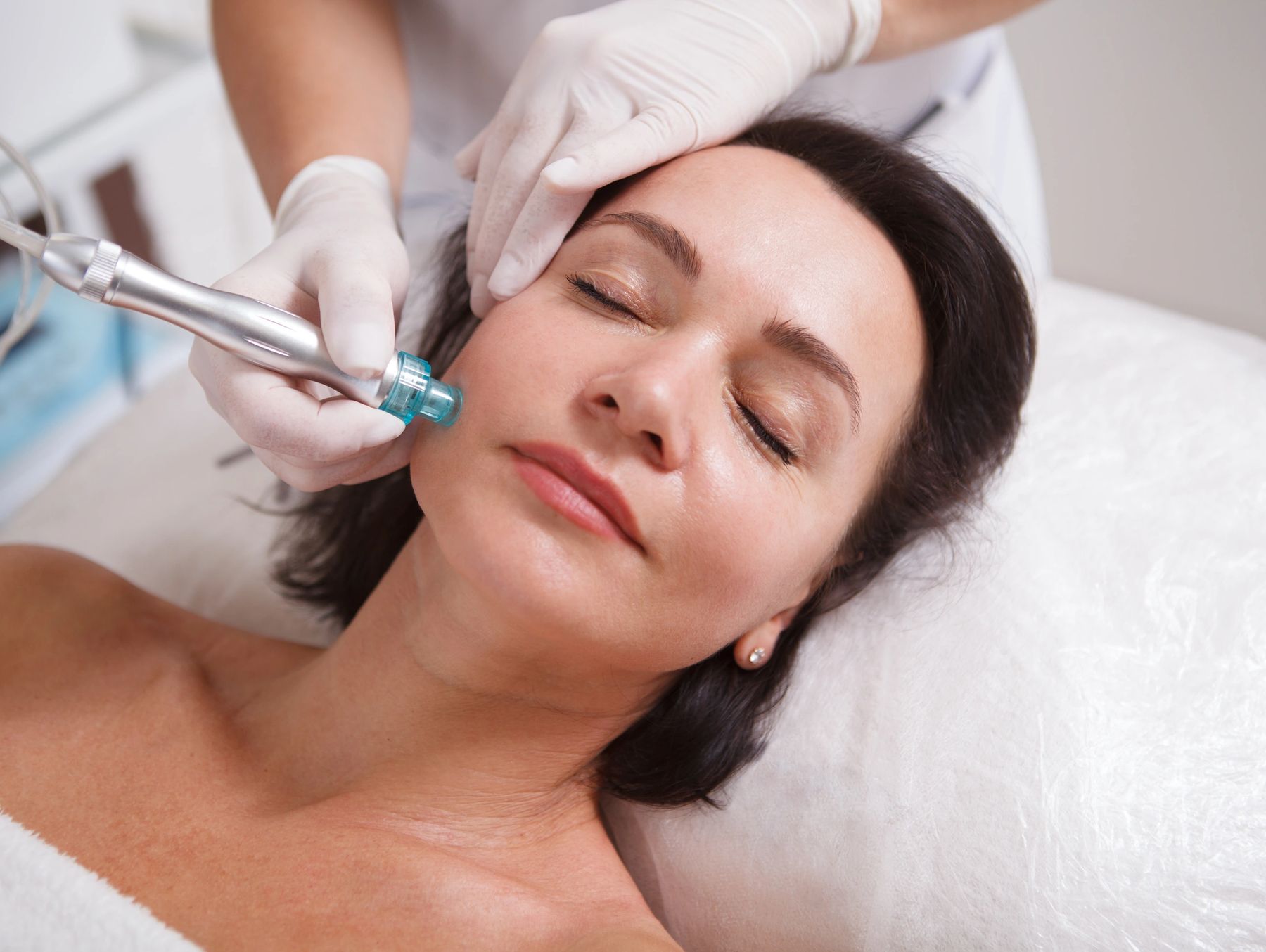 Esthetician performing a skin treatment on a relaxed client